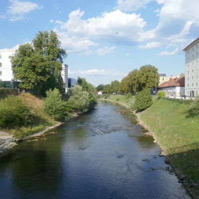pogled z mostu na reko Ljubljanico in stavbo Cukrarne na desnem bregu
